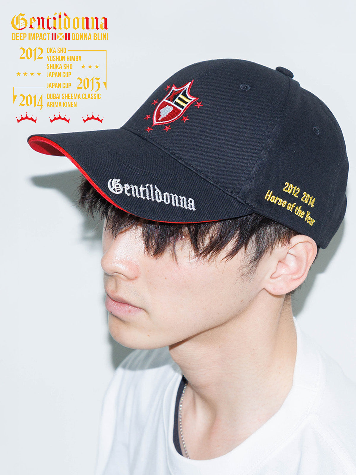 Model wearing a black Gentildonna baseball cap with an embroidered crest and red-trimmed brim, shown in profile.