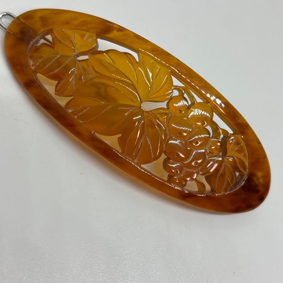 Oval carved tortoiseshell hair clip (kanzashi) with a grape and leaf motif on a white background.