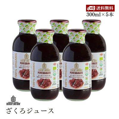 Five glass bottles of pomegranate juice with white labels and green-patterned caps arranged together.