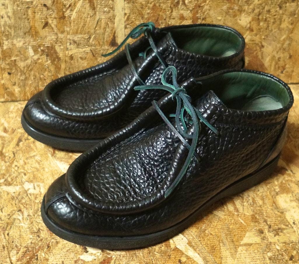Pair of black GEOX leather moc-toe chukka/moc boots shown from an angled top-front view on a wooden surface.