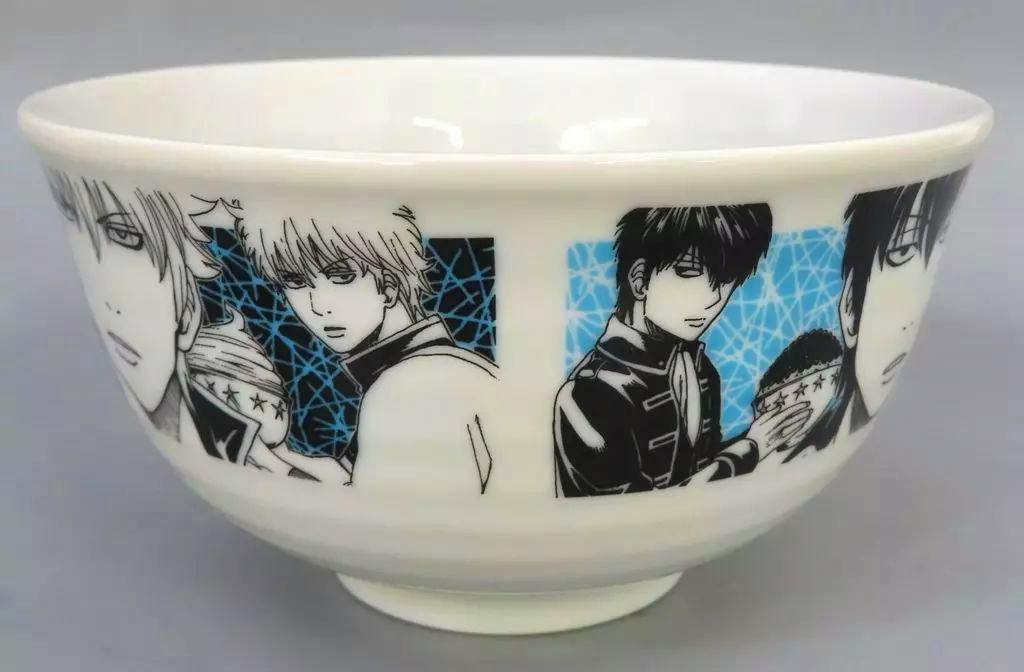 White ceramic donburi bowl showing black-and-blue manga-style character illustrations printed around the exterior.