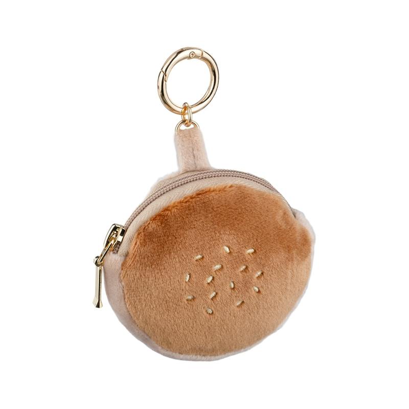 A round plush anpan-style polyester pouch with a zipper and a gold keyring, brown top with seed-like embroidery.