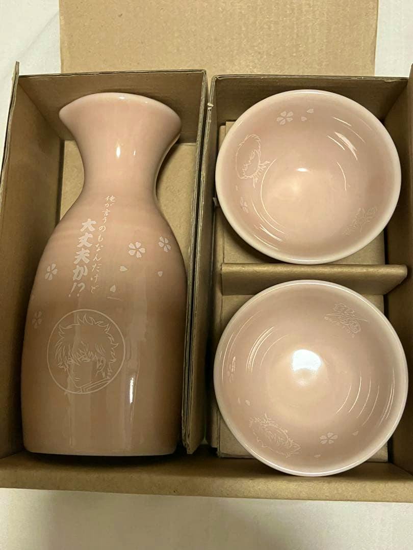 Pink ceramic sakazuki set with a tokkuri and two small cups in a cardboard box, each piece showing etched Gintama character illustrations.
