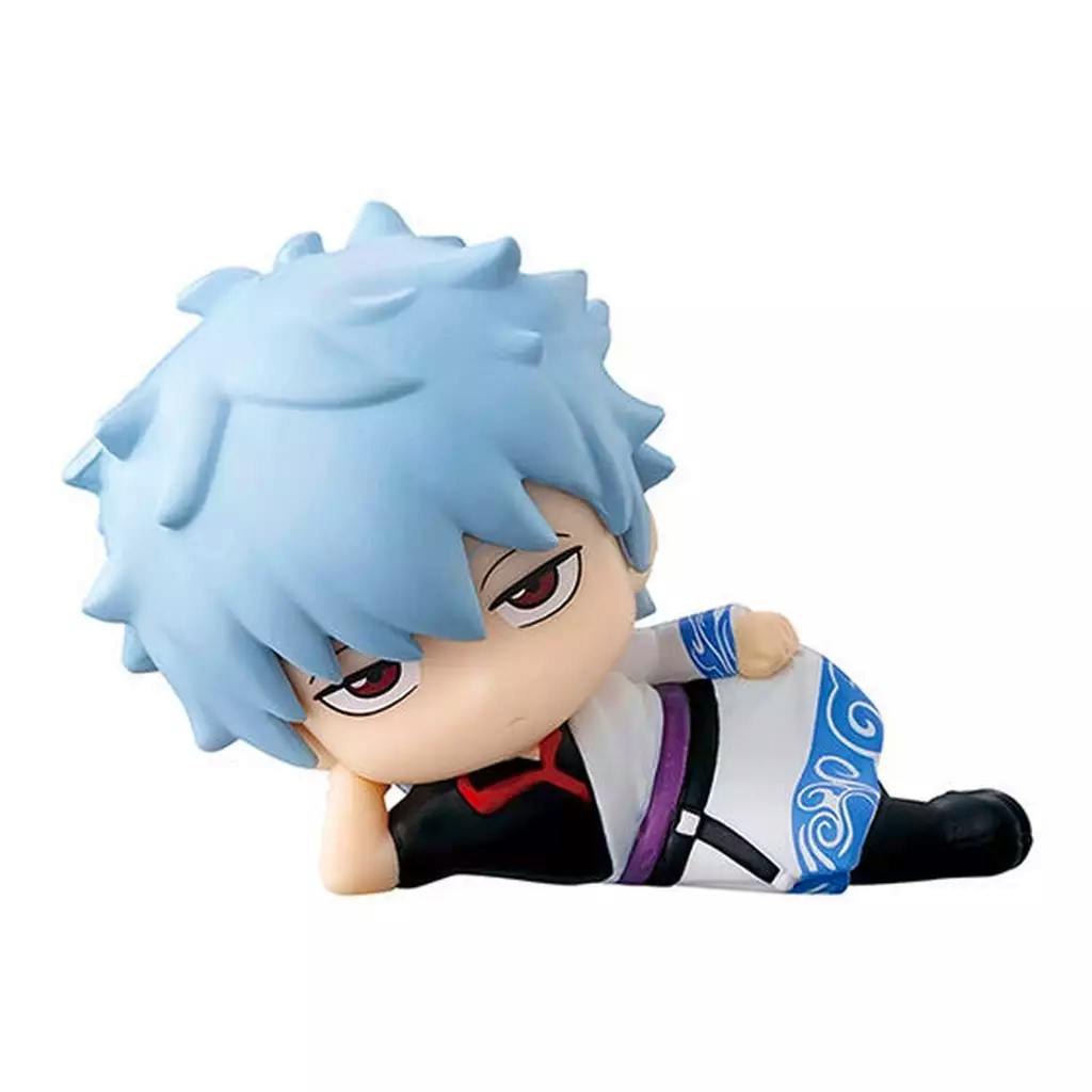 A trading plastic figure of Sakata Gintoki lying on his side with light blue hair, red‑tinted eyes, and his white-and-blue outfit visible.