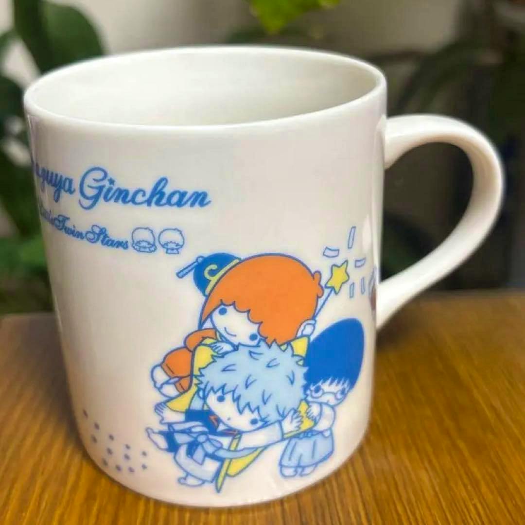 White ceramic mug showing Gintama × Sanrio Kiki & Lala collaboration artwork of chibi characters on the side.