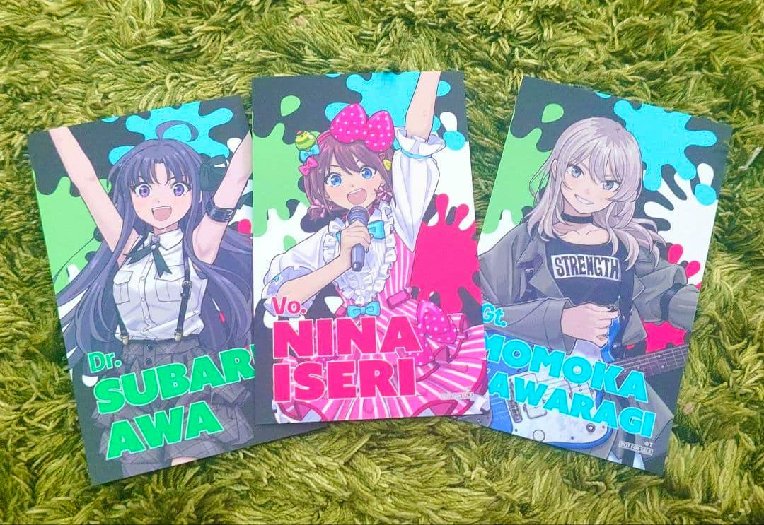 Three illustrated photocards from the photocard bulk set arranged on a green rug.