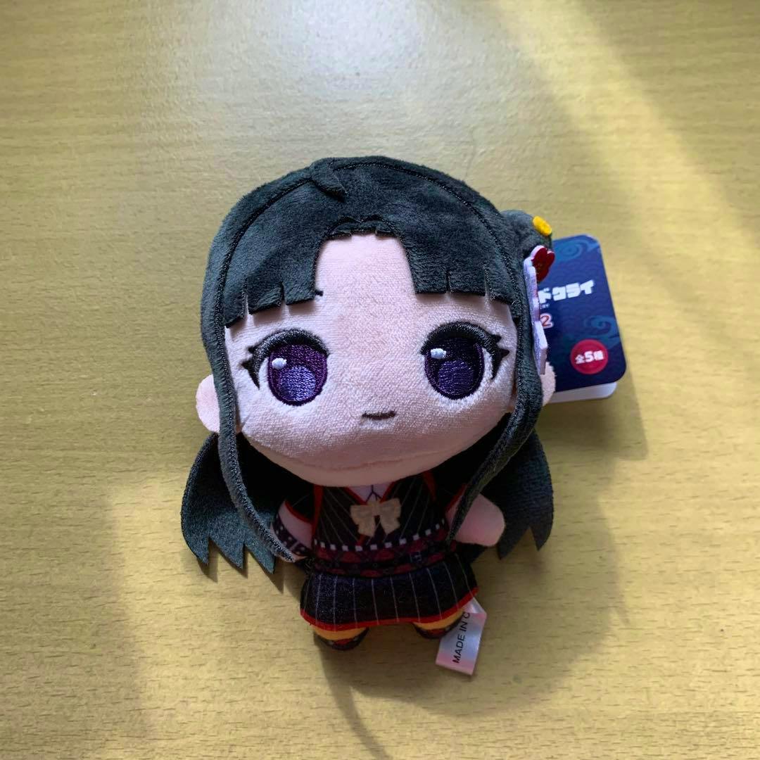 Front view of the ガールズバンドクライ vol.2 ぷちっしゅ 安和すばる plush doll on a wooden surface with its tag visible.