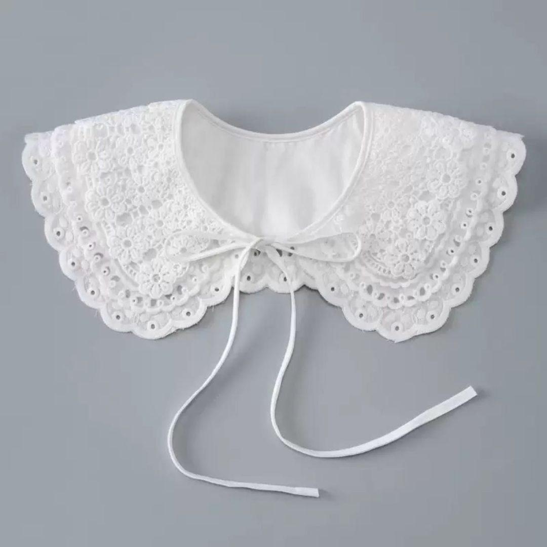 White lace detachable children’s collar with scalloped edges and tie strings laid flat.