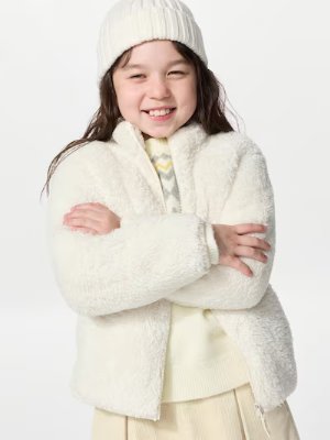 Girl wearing a white fluffy children's jacket against a plain white background.