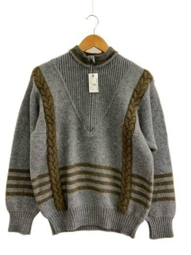 Front view of a gray wool sweater with brown cable-knit vertical panels and brown striped hem, hanging on a wooden hanger with a tag.