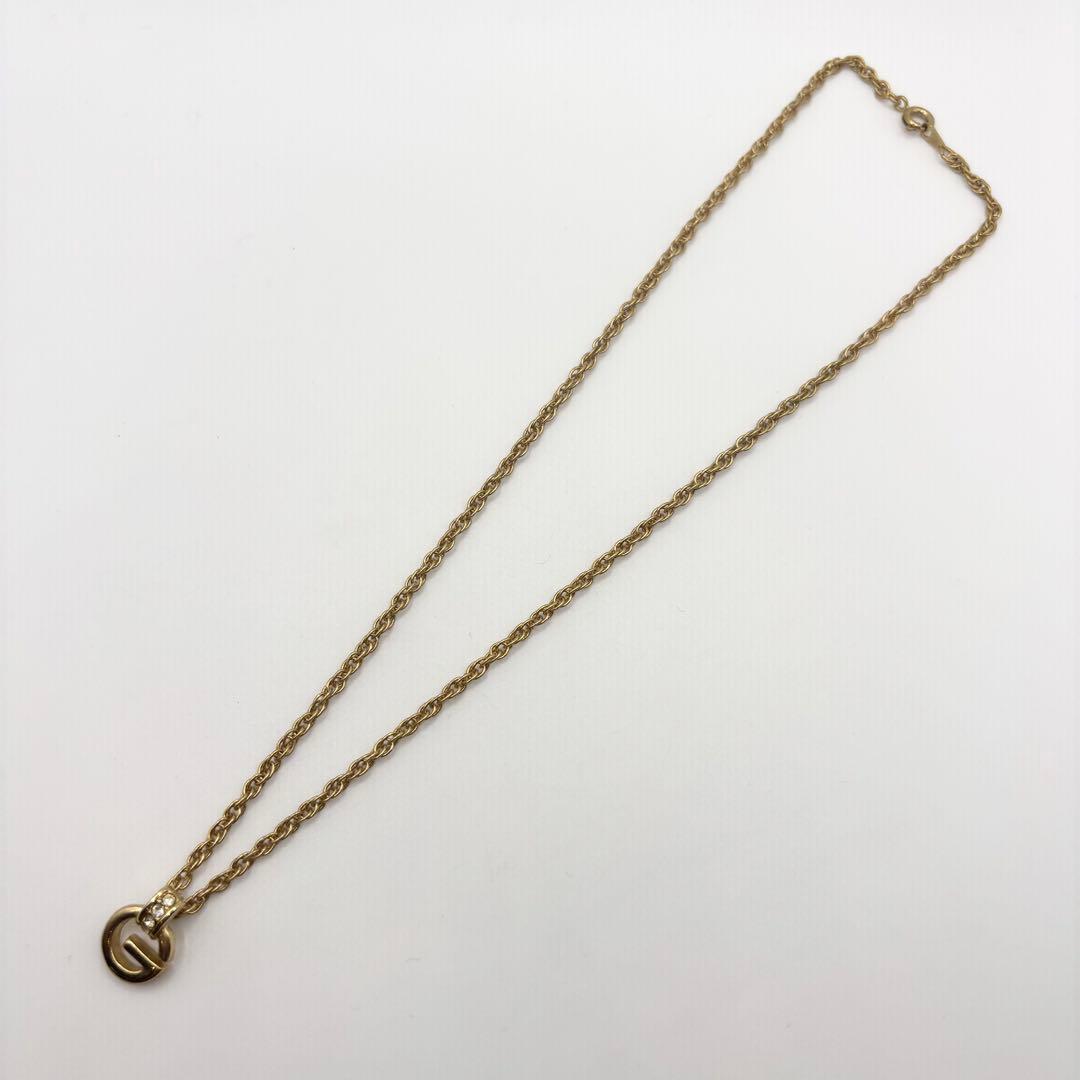 Gold-colored GIVENCHY G-logo necklace with rhinestone-studded bail on a white background.