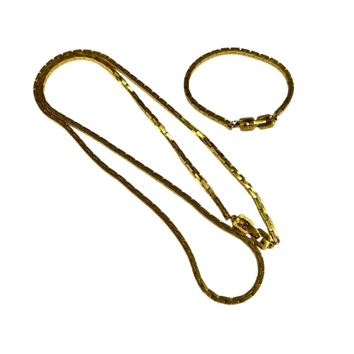Gold-colored chain necklace and matching bracelet laid on a white background.