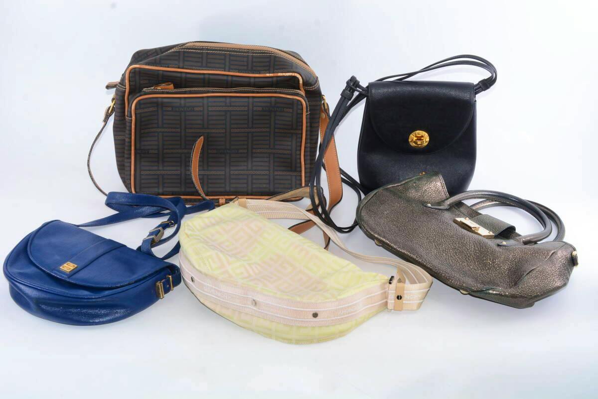 Five bags, including a Givenchy monogram shoulder bag and other leather and canvas handbags, arranged on a white background.