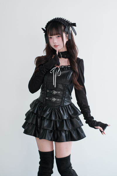 Model wearing a black synthetic leather women's dress with a corset-style bodice and tiered ruffled skirt.