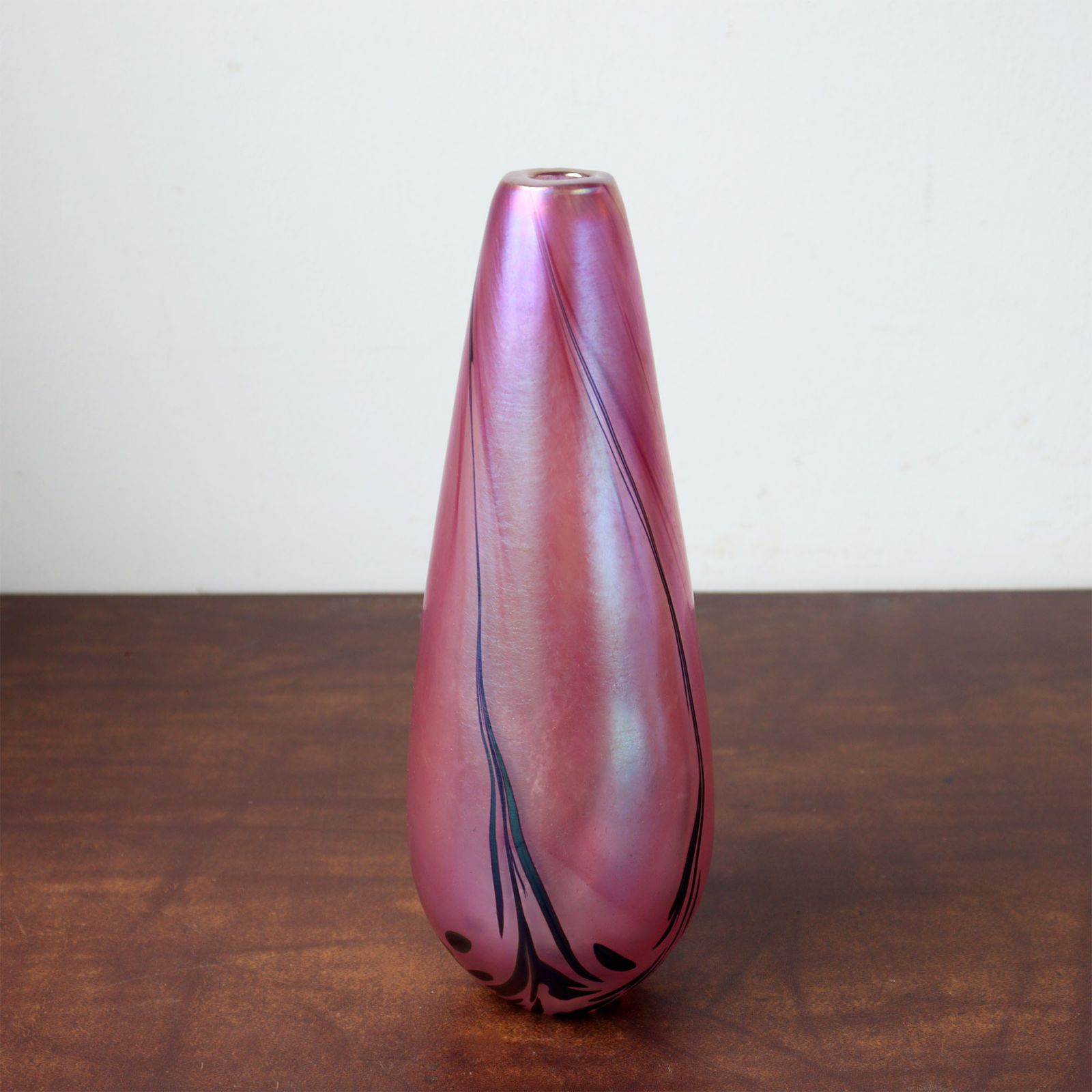 Pink iridescent GLASFORM glass flower vase photographed upright on a wooden surface against a white background.