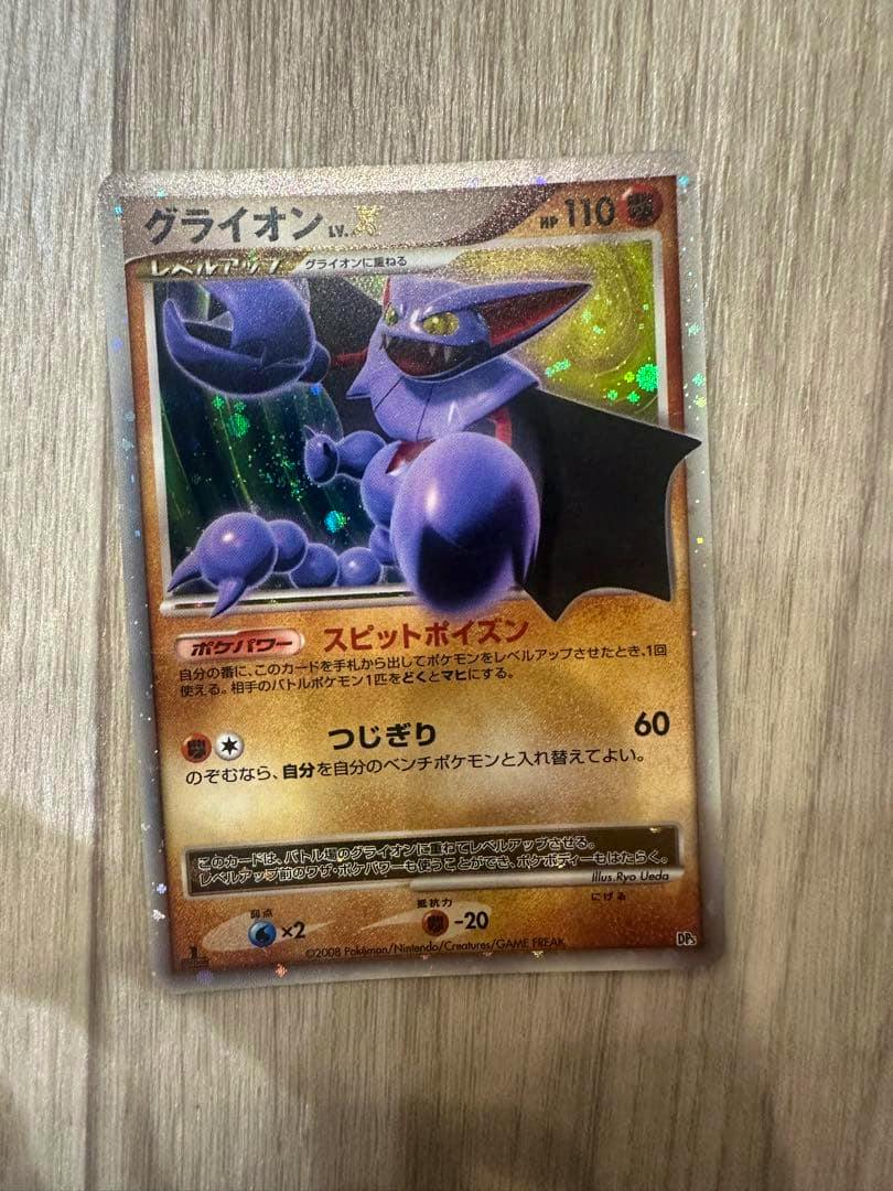 Photo of the グライオン LV.X trading card front placed on a wood surface showing the full card.