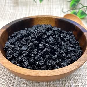 A wooden bowl filled with dried wild blueberries placed on a textured surface.