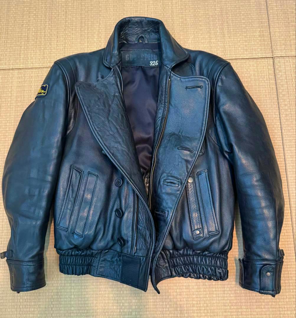 Front view of a black GOD‑SPEED 326 men's cow leather rider jacket laid flat showing collar, zipper, pockets, and elastic hem.