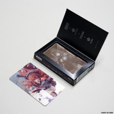 Opened black NIKKE chocolate box with chocolates visible and a collectible character card beside it.