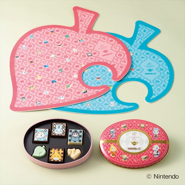 Open Godiva 6-piece chocolate tin displayed with pink and blue leaf-shaped tea mats.