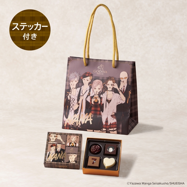 Open box of four Godiva chocolates displayed next to a Godiva×NANA illustrated gift bag and sticker.