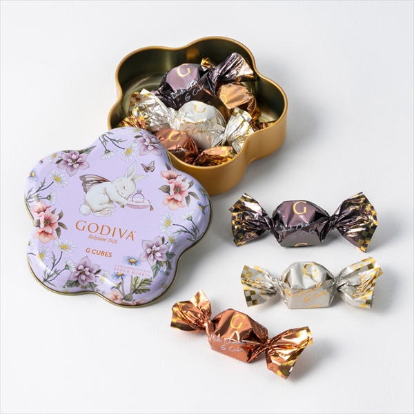 Flower-shaped Godiva tin of G Cube assorted chocolates (7-piece set) with several individually wrapped chocolate cubes displayed.
