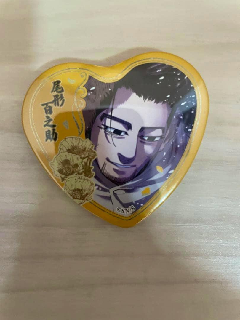 Heart-shaped can badge showing Ogata Hyakunosuke character illustration from Golden Kamuy placed on a light wooden surface.