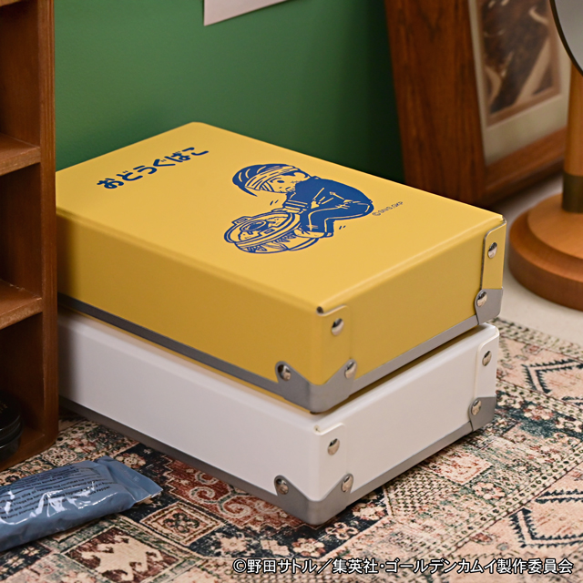 A yellow steel toolbox labeled 'おどうぐばこ' with a blue illustration, shown stacked on a white box.