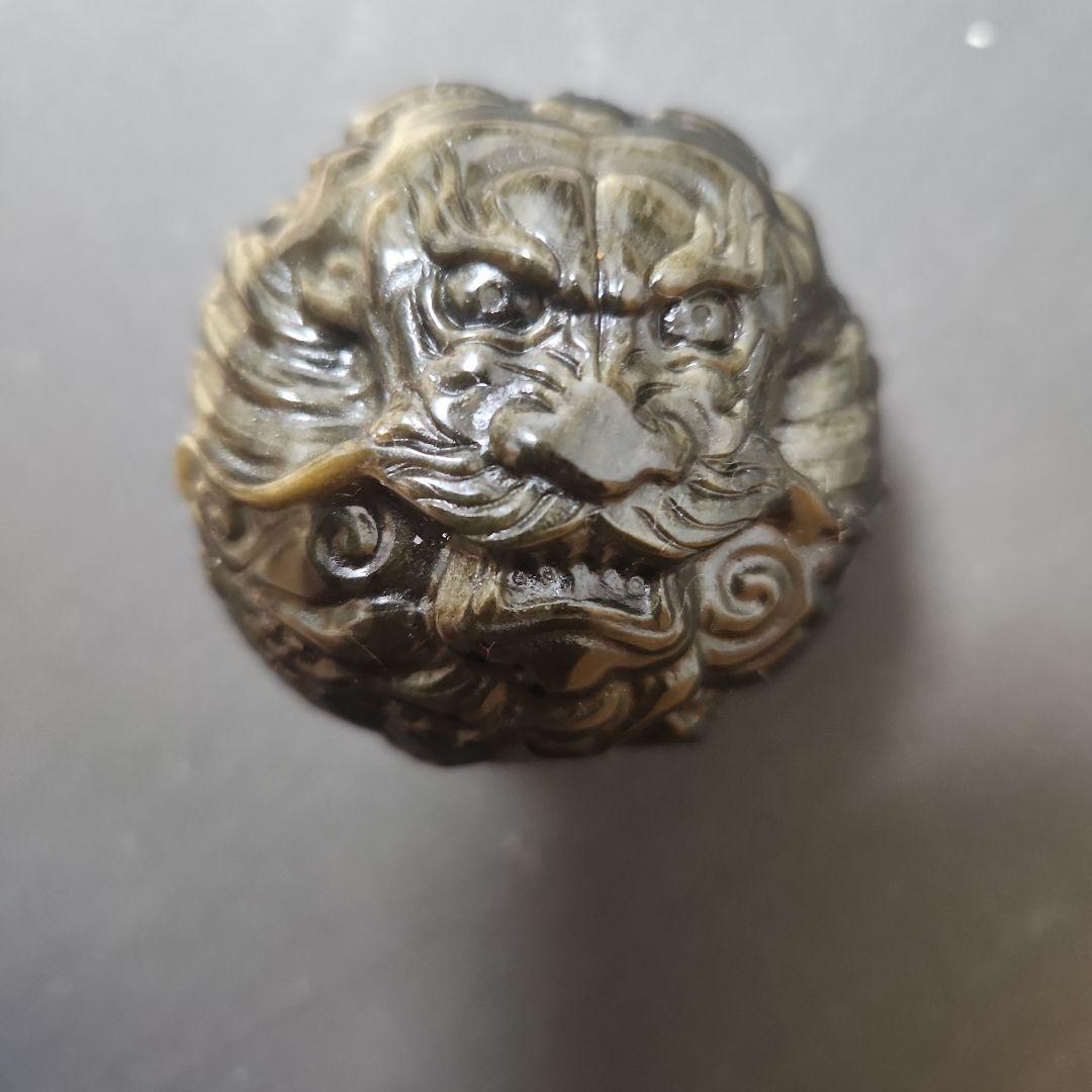 Carved round dragon sphere ornament made from golden obsidian shown on a gray background.