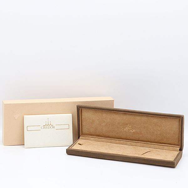 Open brown Credor wristwatch box shown with its cream outer box and a Credor paper card beside it.