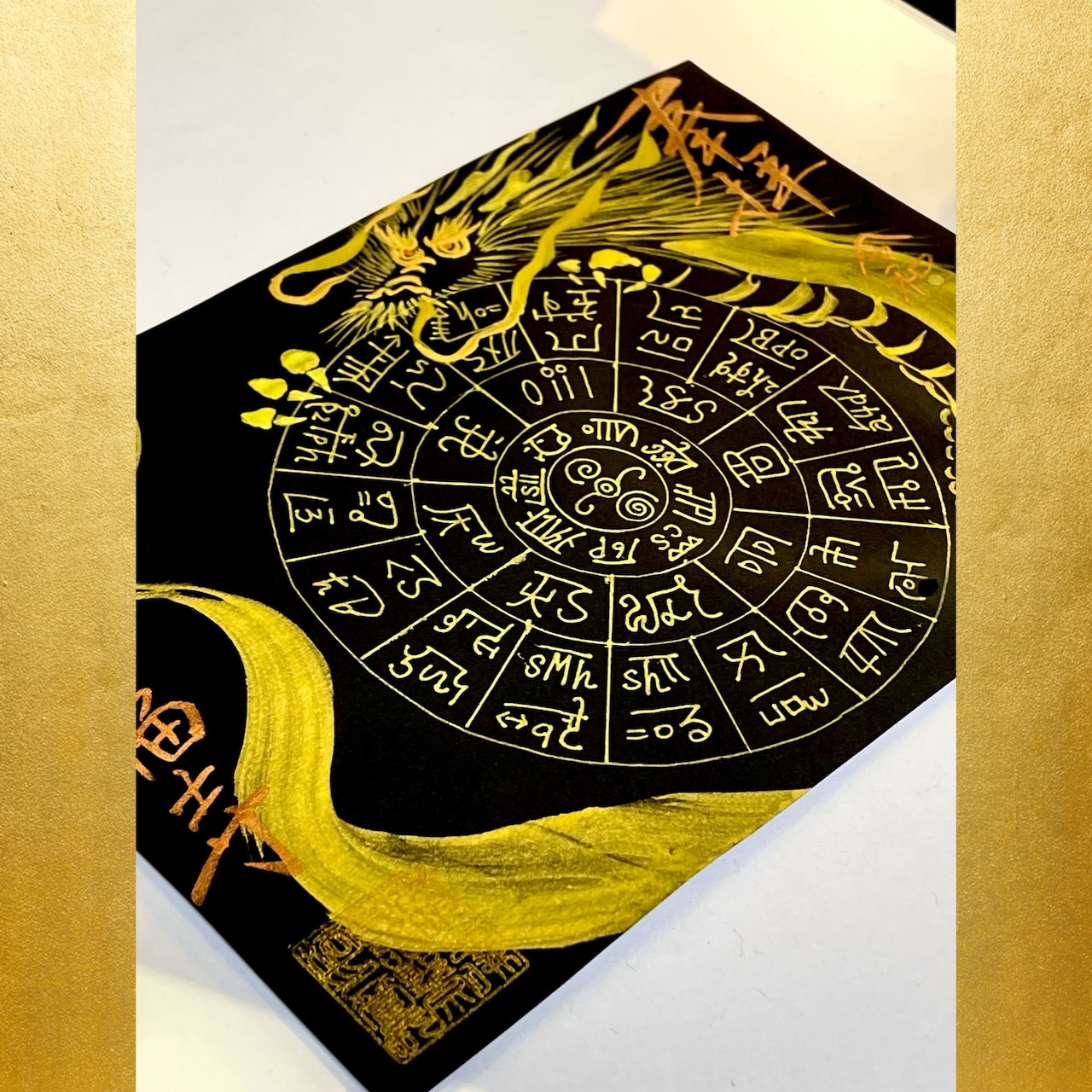 A greeting card showing a black card with a gold dragon and circular Japanese characters photographed on a white surface.