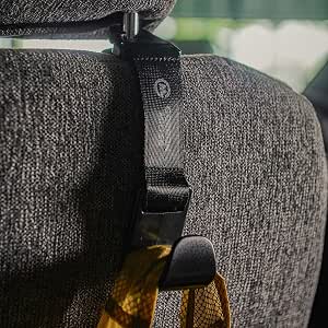 Black car seat hook attached to a headrest strap on a gray seat holding a bag.