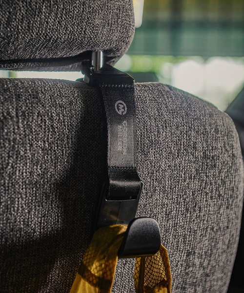 GORDON MILLER Seat Hook with its strap looped around a car headrest and the hook holding a hanging bag.