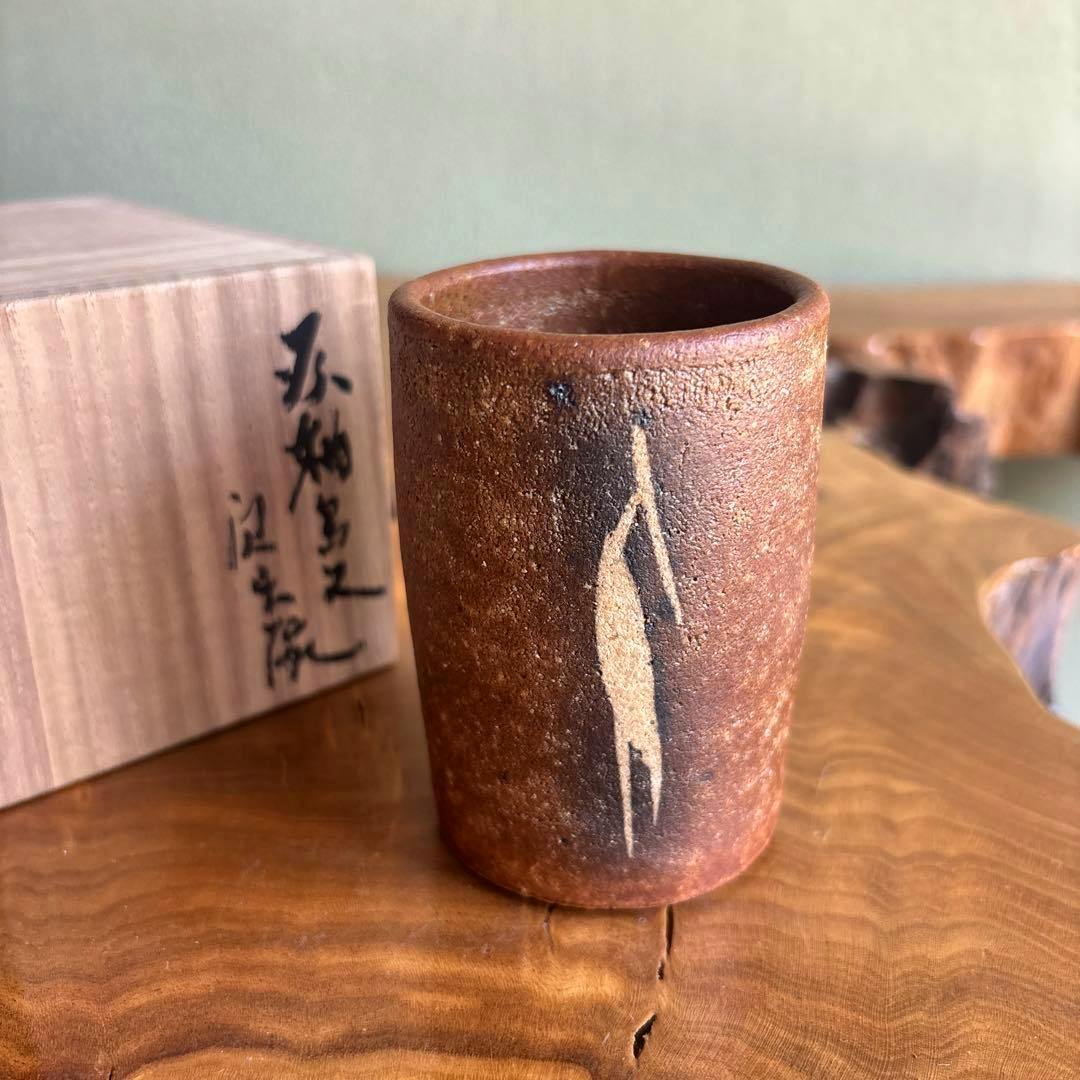 Goro Kawamoto gray-glazed teacup with a bird motif shown next to its wooden tomobako box.