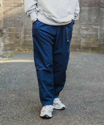 Front view of the Gramicci nylon track pant worn by a model with sneakers and a sweatshirt.