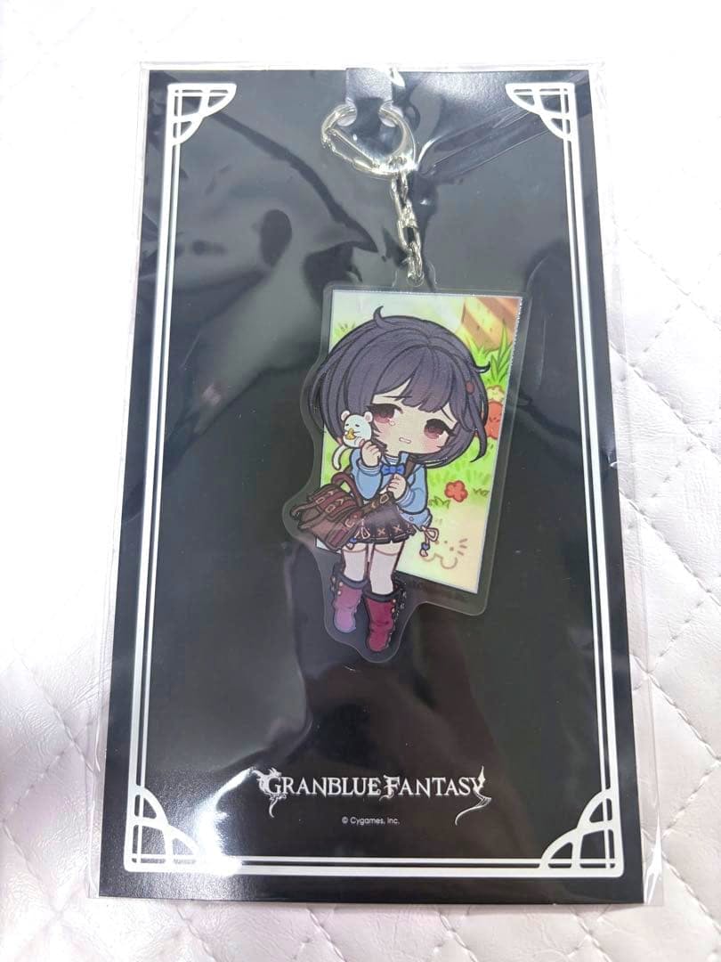 Front view of the reversible acrylic keychain (ビカラ) in its packaging, showing the chibi character artwork on a black backing with the Granblue Fantasy logo.