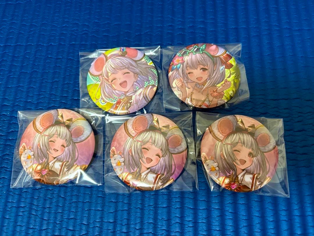 Six sealed round trading can badges featuring Vikala (from Granblue Fantasy) arranged on a blue textured surface.