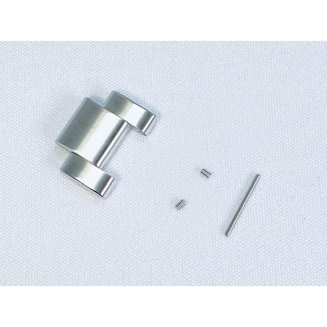 Stainless steel watch band link with two small pins and a rod on white fabric.