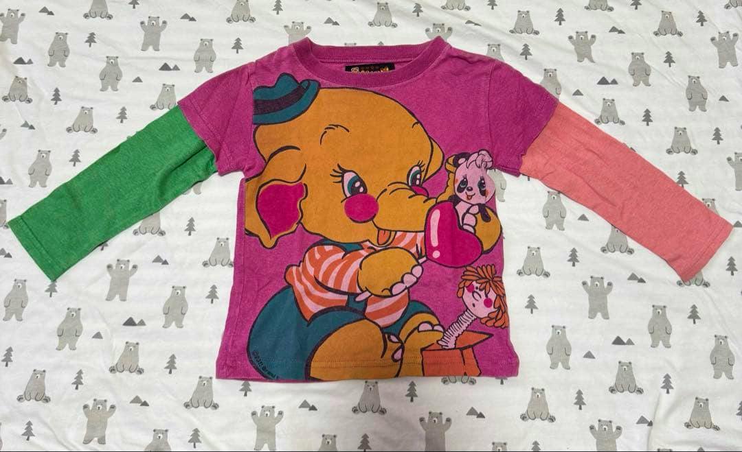 Front view of a children's cotton long-sleeve shirt laid flat, pink with a large elephant graphic and contrasting green and coral sleeves.