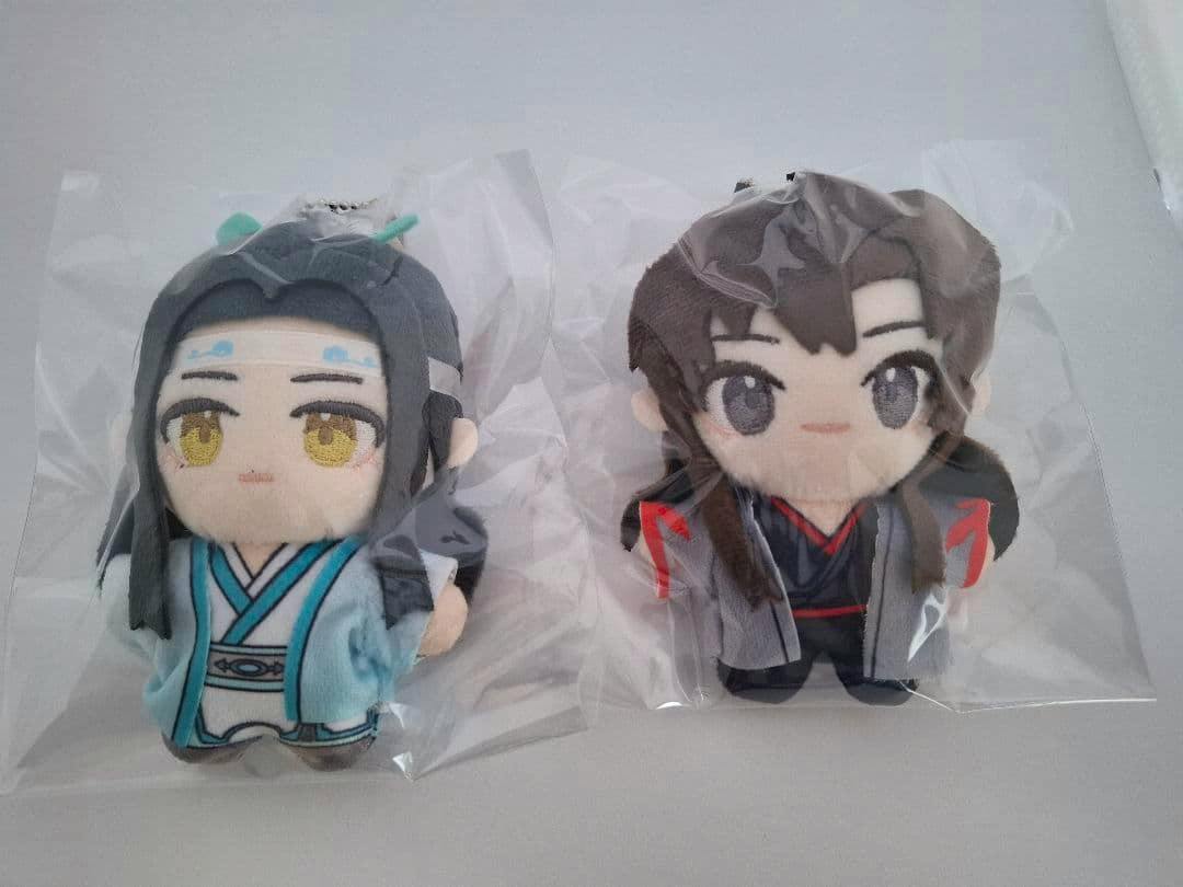 Two plush keychain toys from the set, one in pale blue robes and one in dark clothing, each in clear plastic bags on a light background.