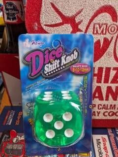 Blister-packaged green dice-shaped car shift knob with white pips shown against a display background.