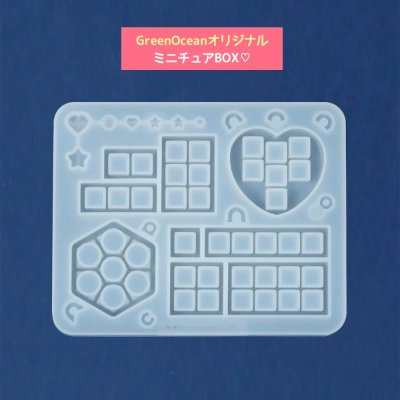 Translucent silicone mold for miniature box shapes (heart, hexagon, rectangles) on a blue background.