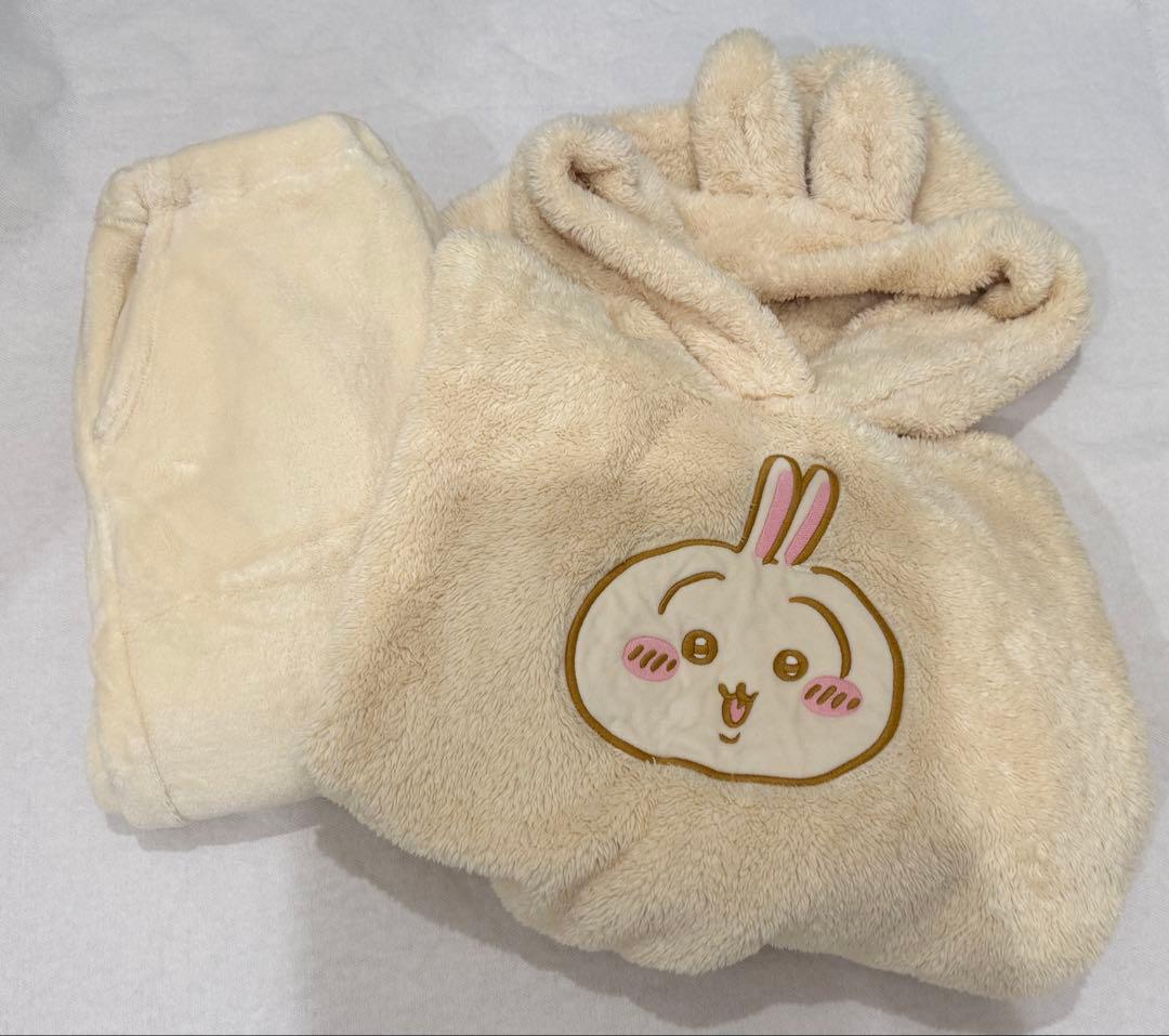 Beige fleece women's pajama set with a rabbit-eared hood and a character face on the front, shown folded with matching pants.
