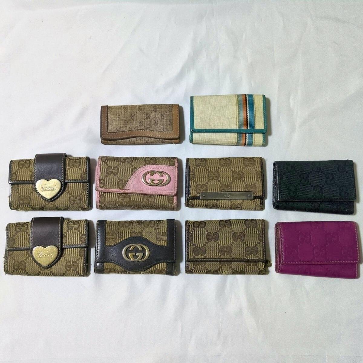 A set of Gucci key cases and small wallets in GG canvas and leather arranged on a white background.