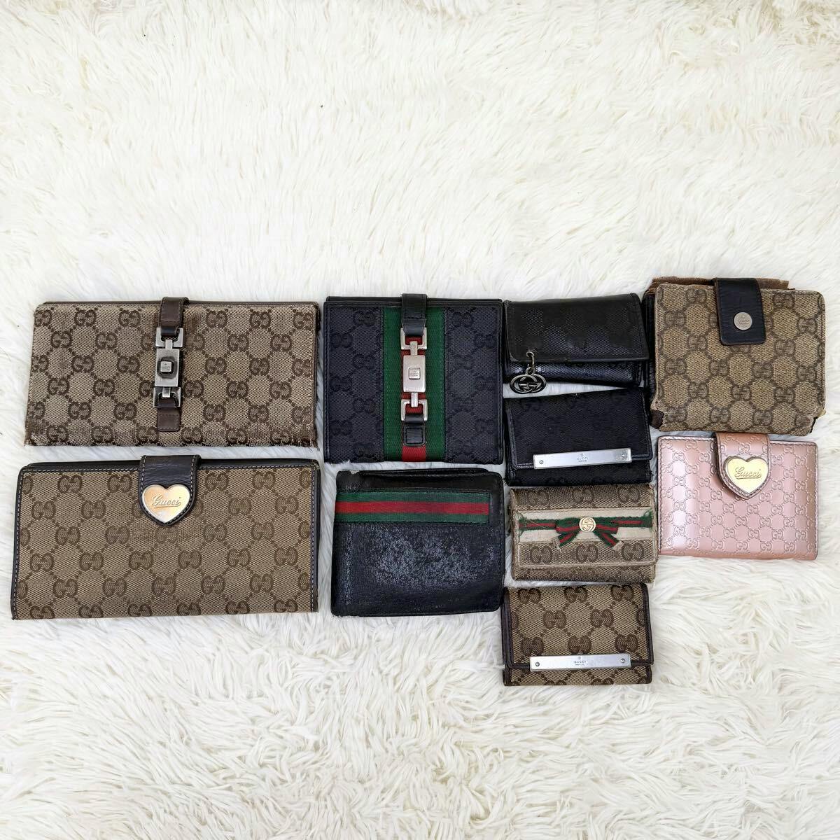 Multiple Gucci canvas wallets and small bags arranged on a white fur background.