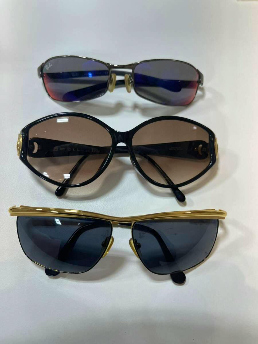 Three pairs of brand sunglasses (Gucci, Ray‑Ban, Dior) arranged on a white background.