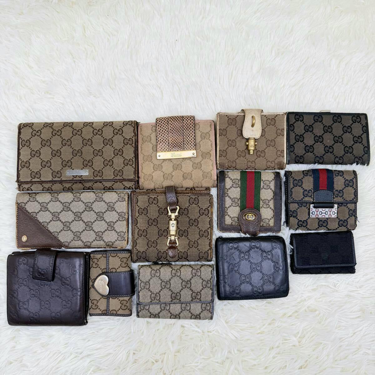 Top-down photo of a bulk set of Gucci wallets and small leather accessories in GG canvas and leather arranged on a white fur background.