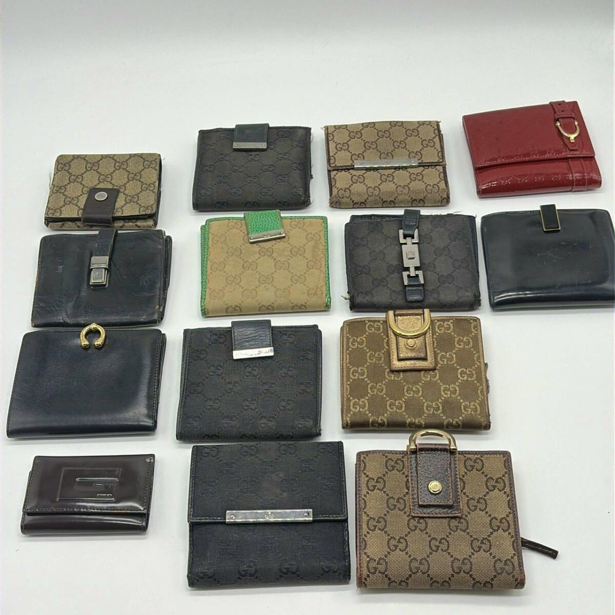 Fourteen Gucci wallets and small leather goods, many with GG canvas patterns, arranged on a white background.