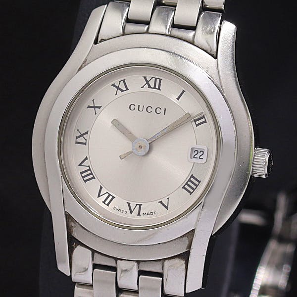 Front view of a silver Gucci men's wristwatch showing a silver dial with Roman numerals and a date window at 3 o'clock.