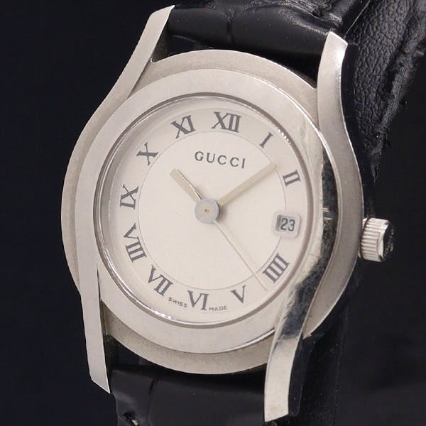 Front view of the GUCCI women's round watch with a silver dial, Roman numerals, date window, and black leather strap.